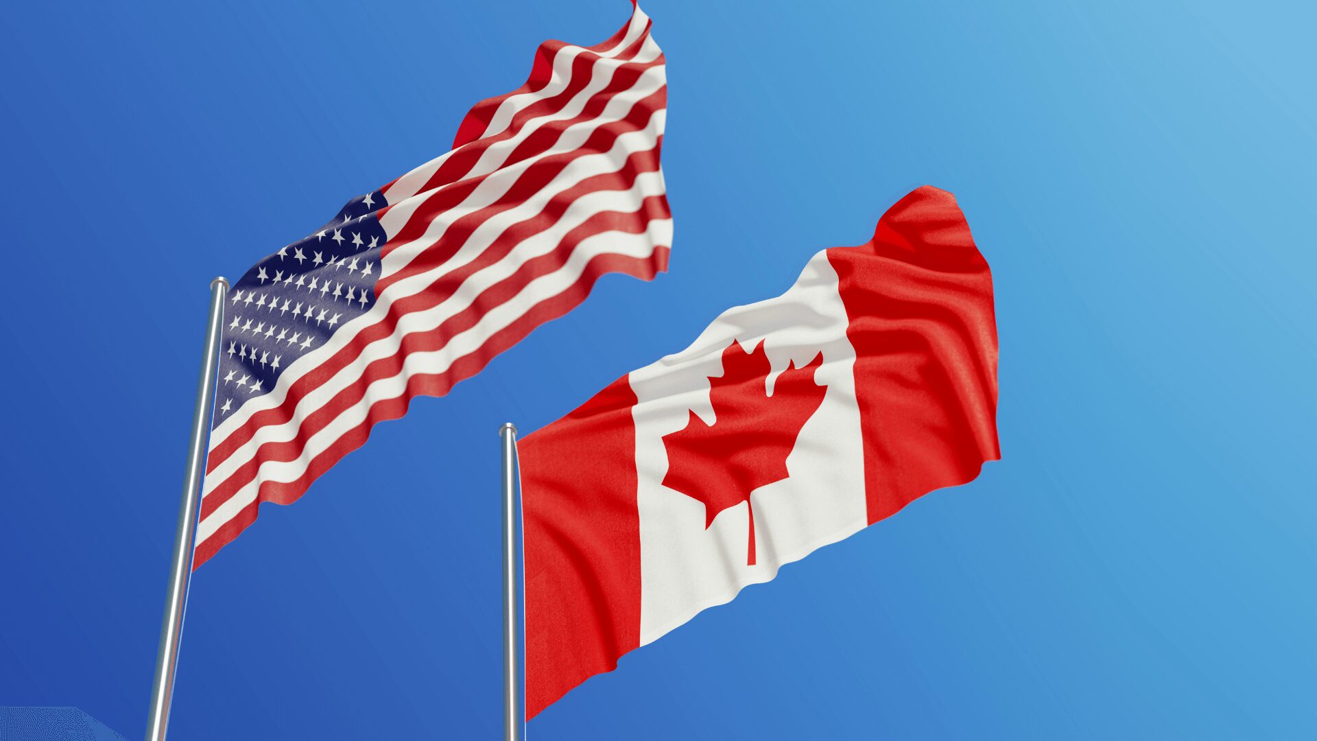 American and Canadian flags waving against sky.