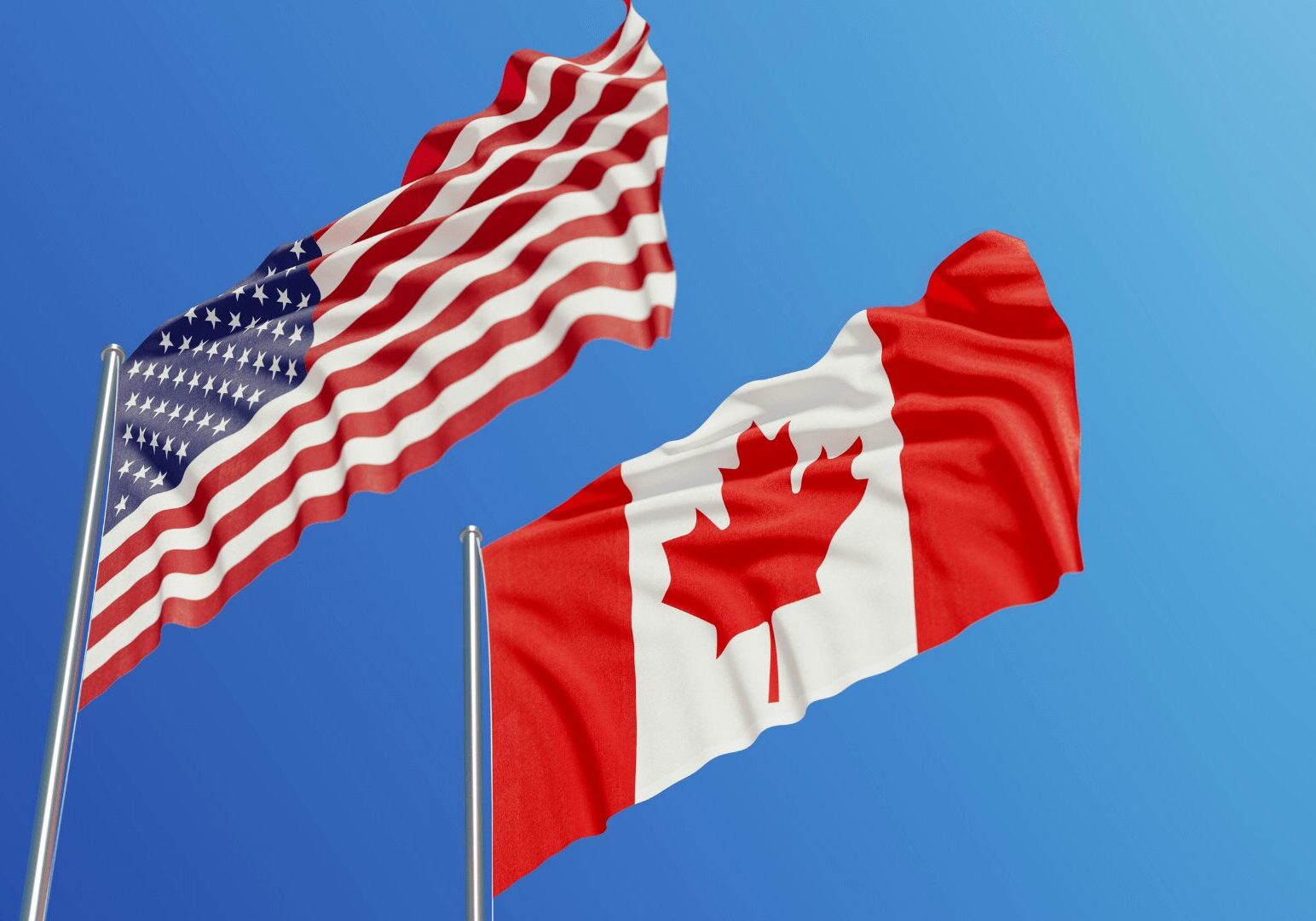 American and Canadian flags waving against sky.